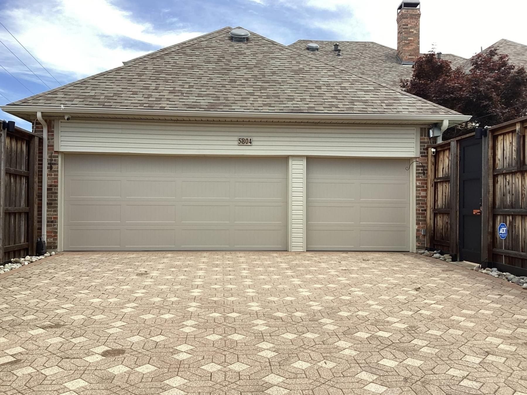 A house with a double garage door and a brick driveway.