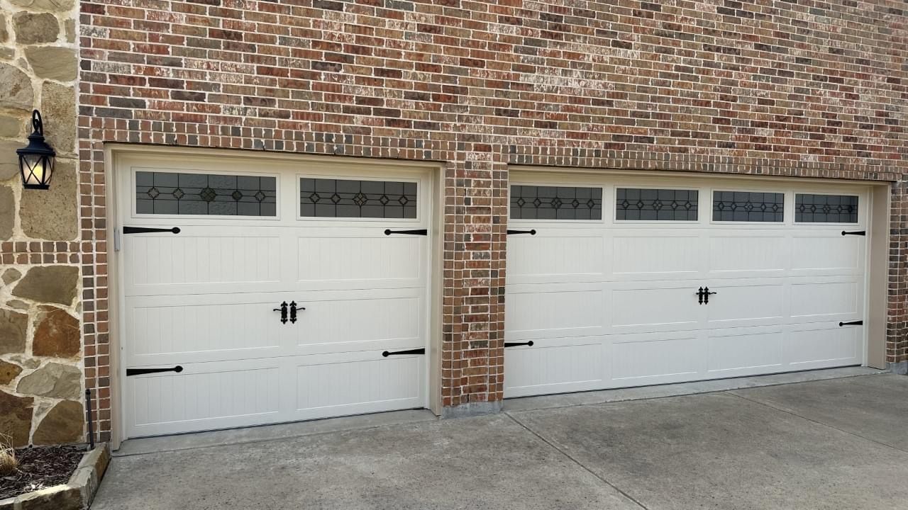 A couple of white garage doors on a brick building.