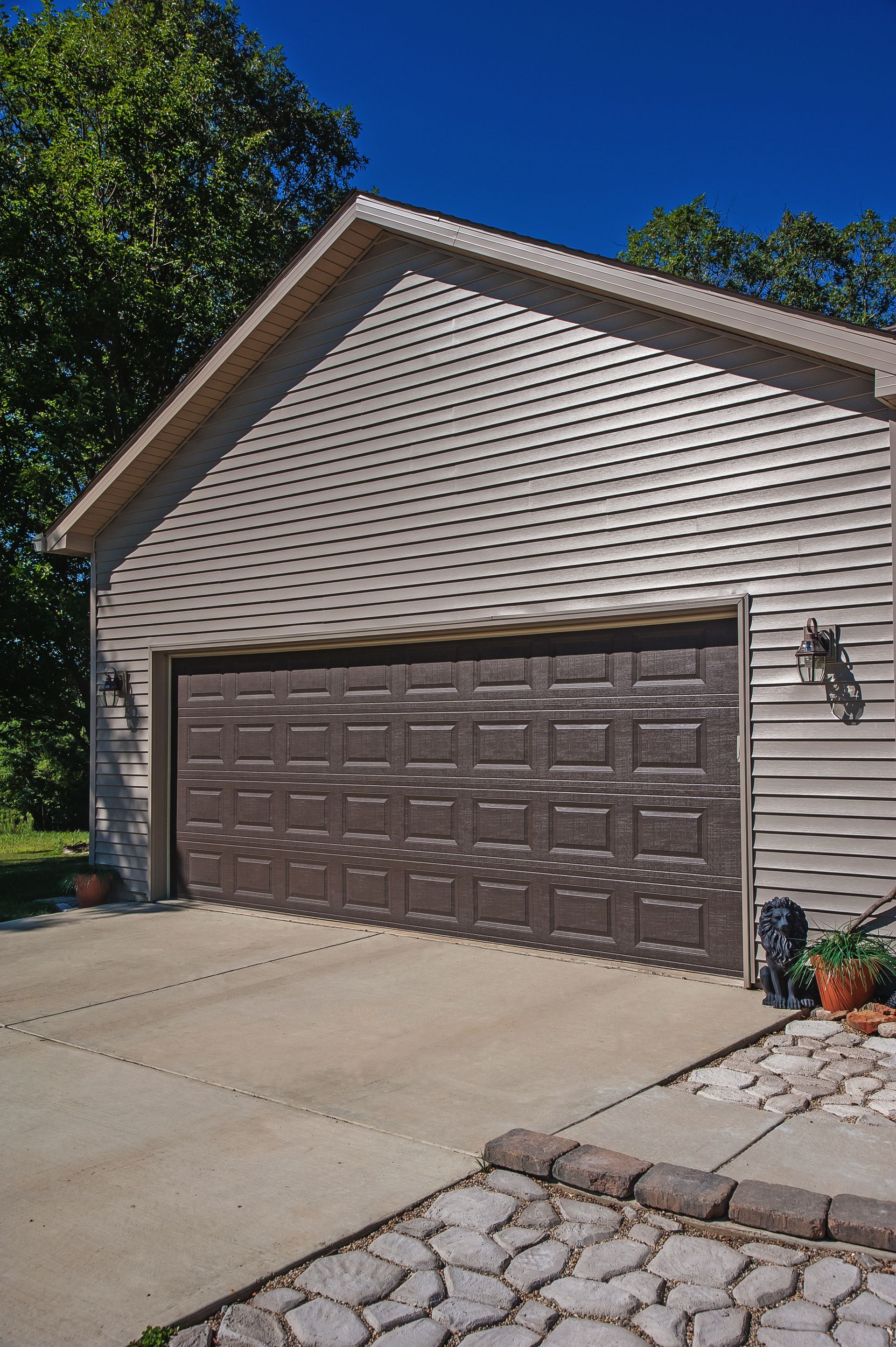 A garage with a brown garage door and a brick driveway.