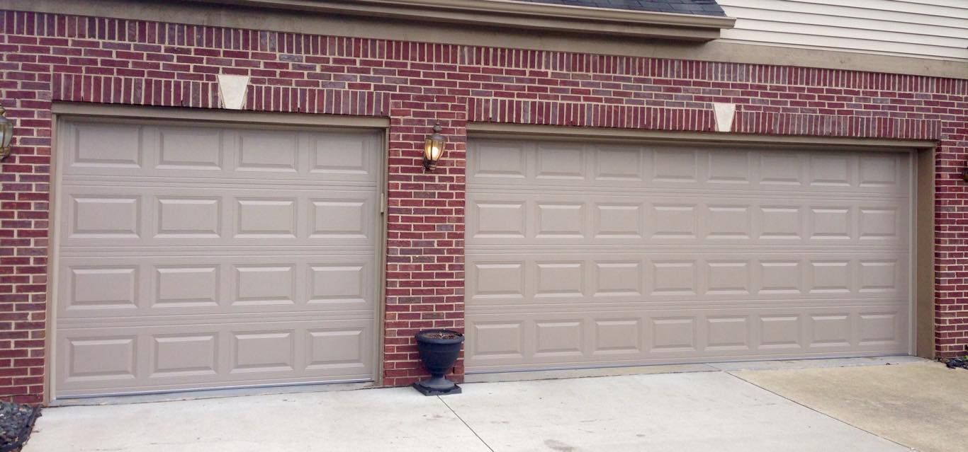 There are two garage doors on the side of a brick building.