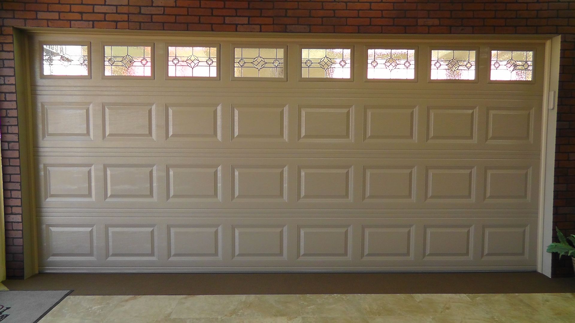 A white garage door with a brick wall behind it