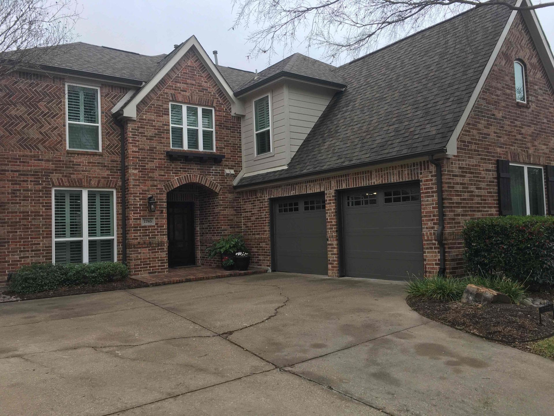 A large brick house with two garage doors and a driveway.