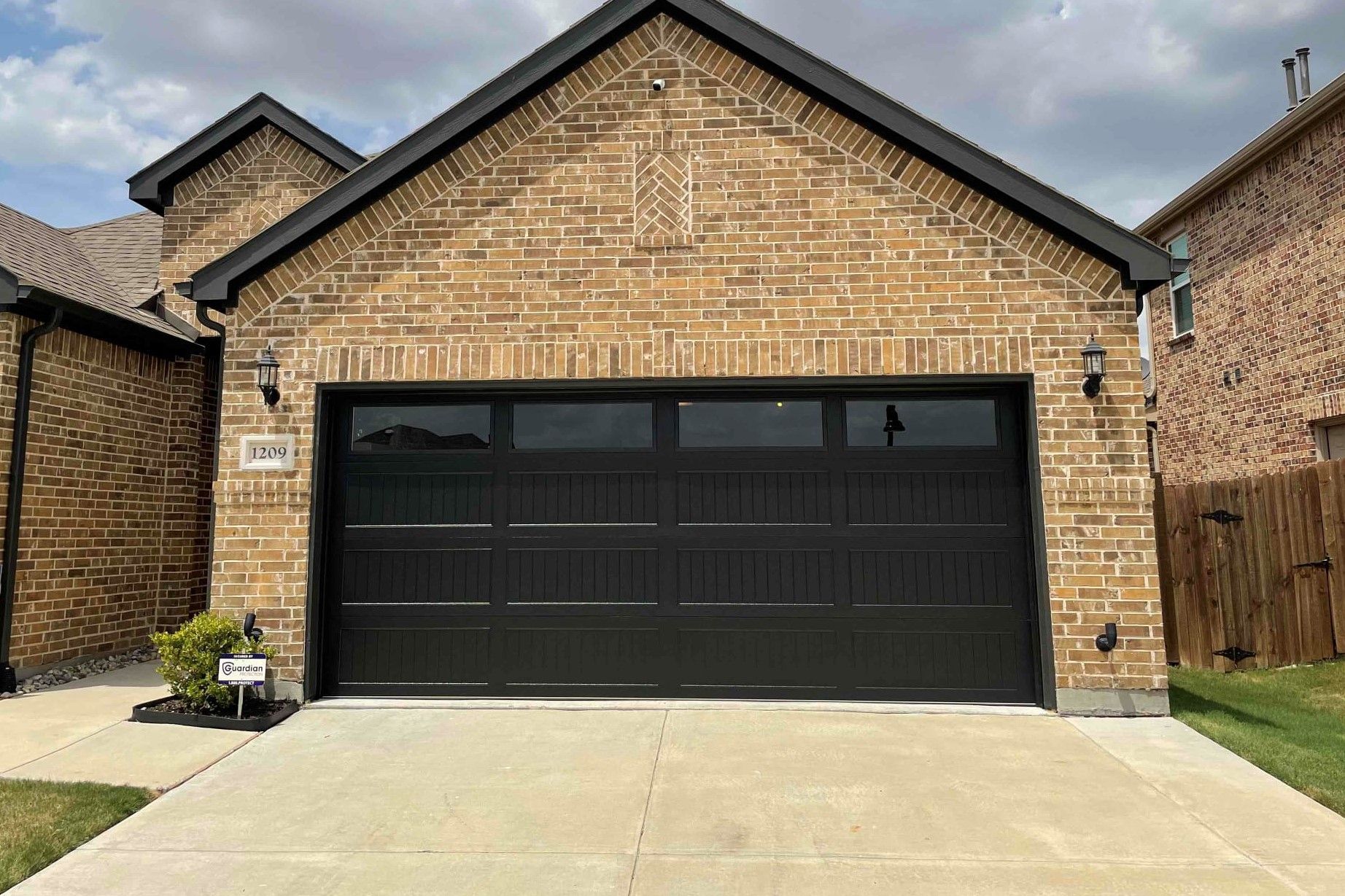 A brick house with a black garage door is for sale.