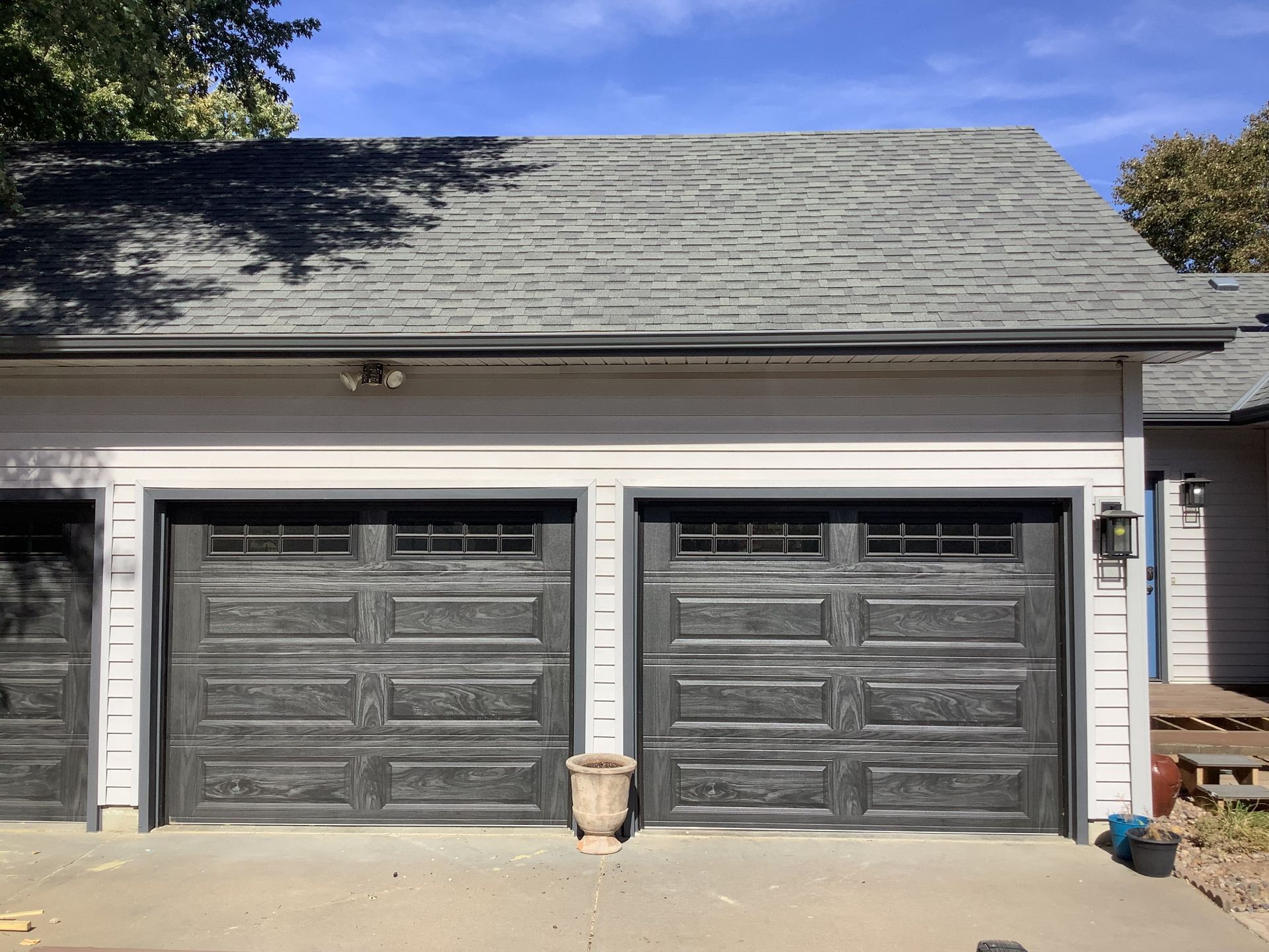 A garage with three black garage doors and a gray roof.
