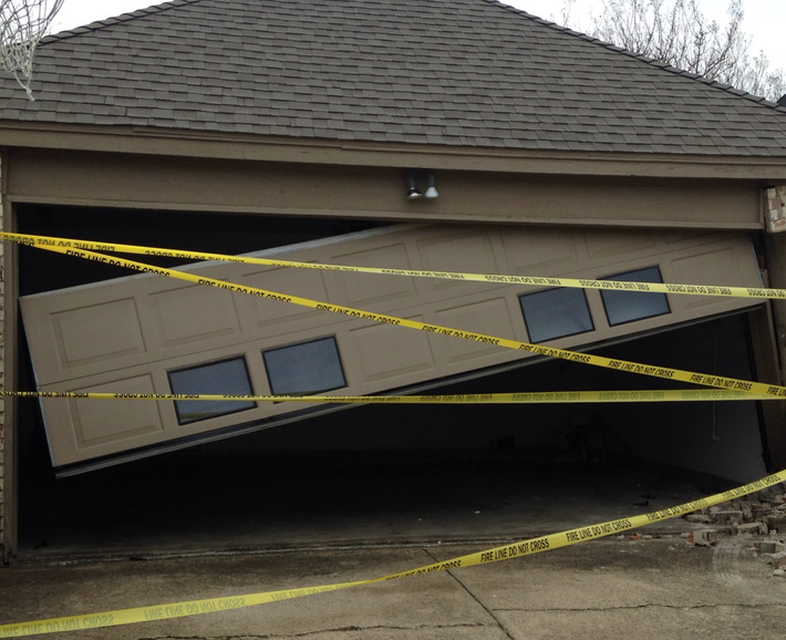 A broken garage door is surrounded by yellow caution tape