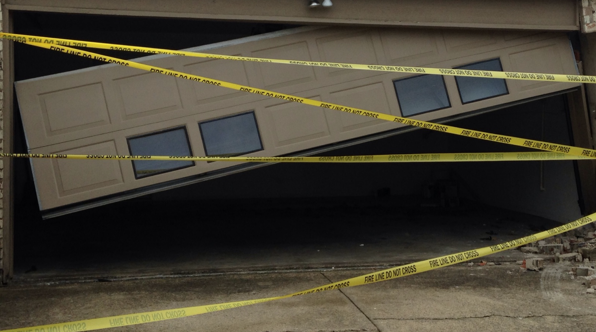 A broken garage door is surrounded by yellow warning tape - Plano, TX 75074, USA- Plano Overhead Garage Door