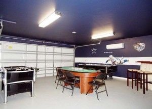 A game room in a garage with a pool table and foosball table.