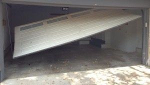 A garage door is broken in half and is sitting on the ground.