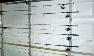 A bunch of fishing rods are hanging on a garage door.