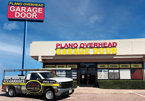 A white truck is parked in front of a building that says plano overhead garage door