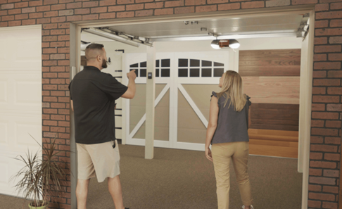 A man and a woman are standing in front of a garage door.