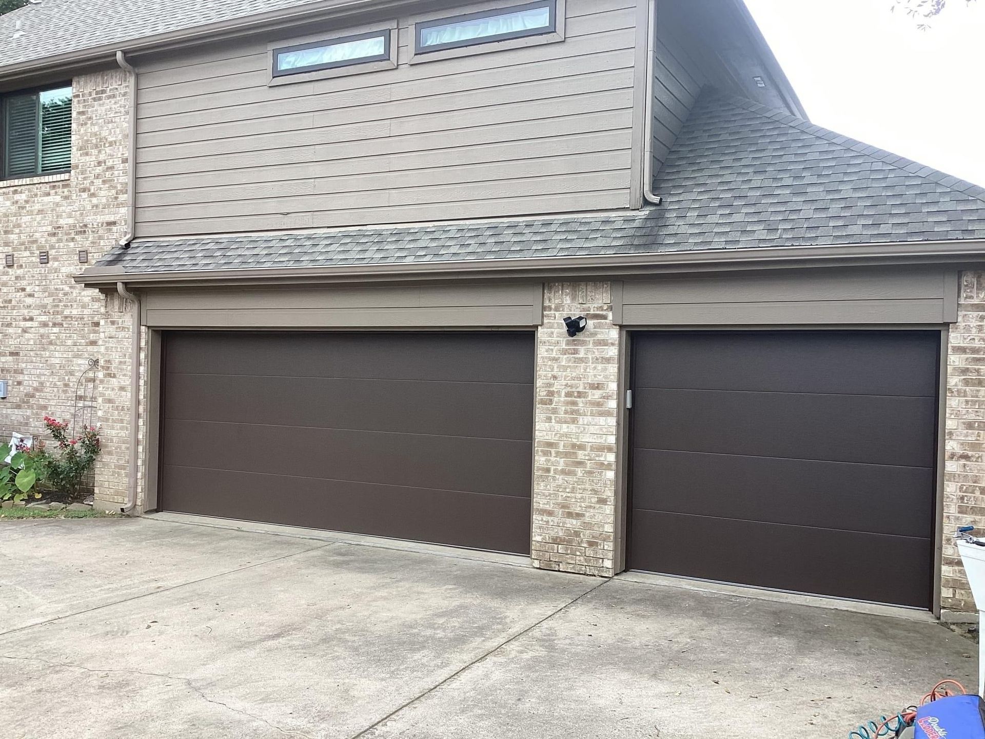 A large brick house with two brown garage doors.