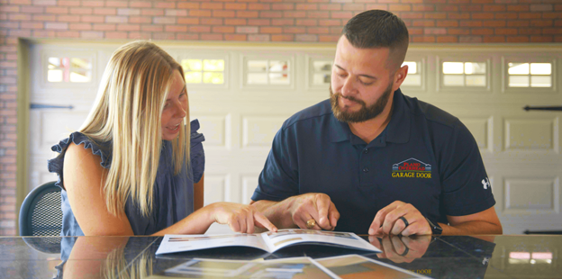 Plano Overhead Garage Door employee showing garage door options brochure in showroom.