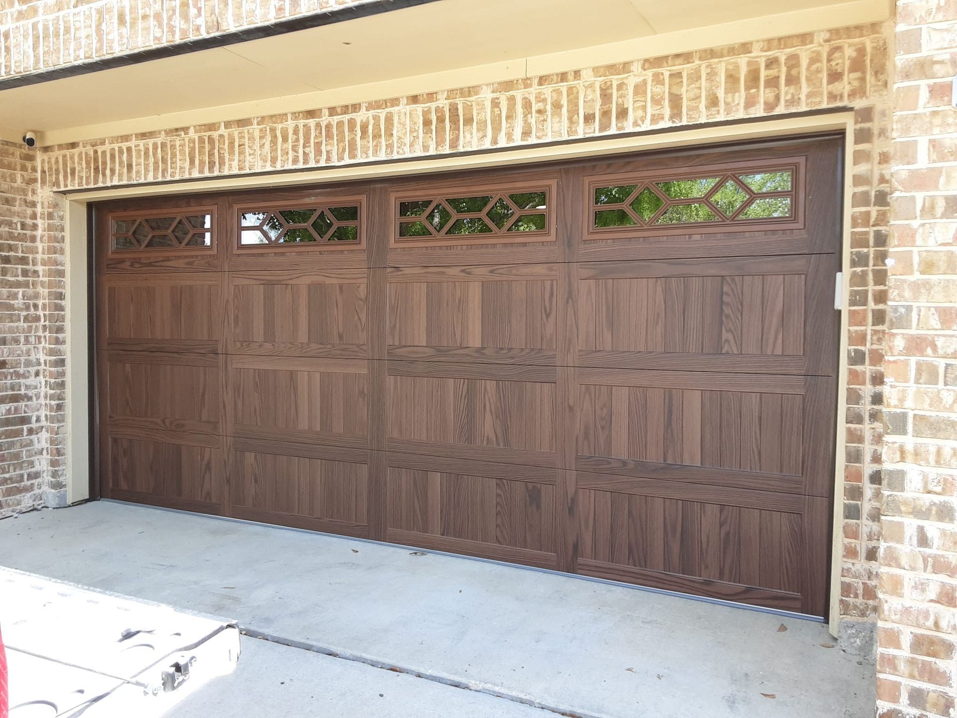 A wooden garage door with a brick wall behind it