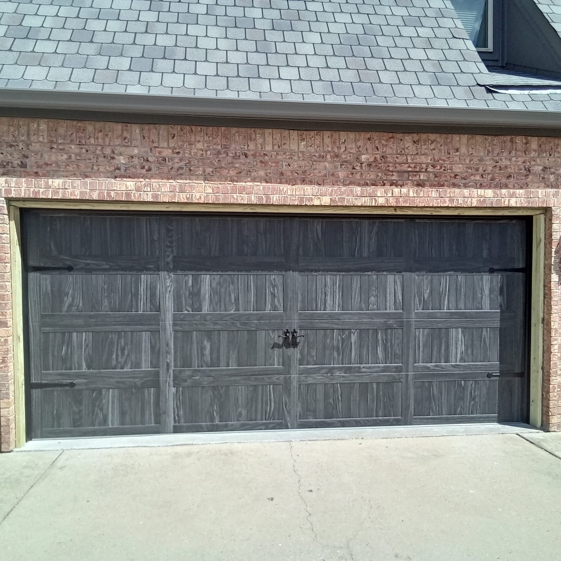 A brick garage with a black door and a slate roof