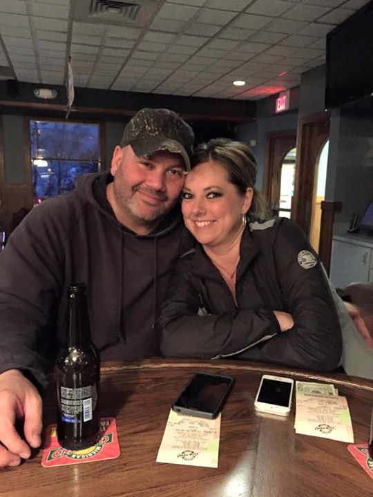A man and a woman are posing for a picture at a bar