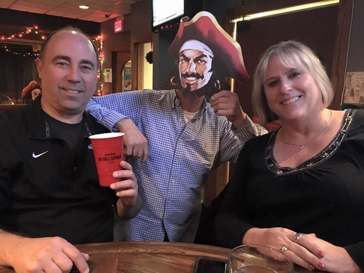 A man is holding a red cup in front of a picture of a pirate