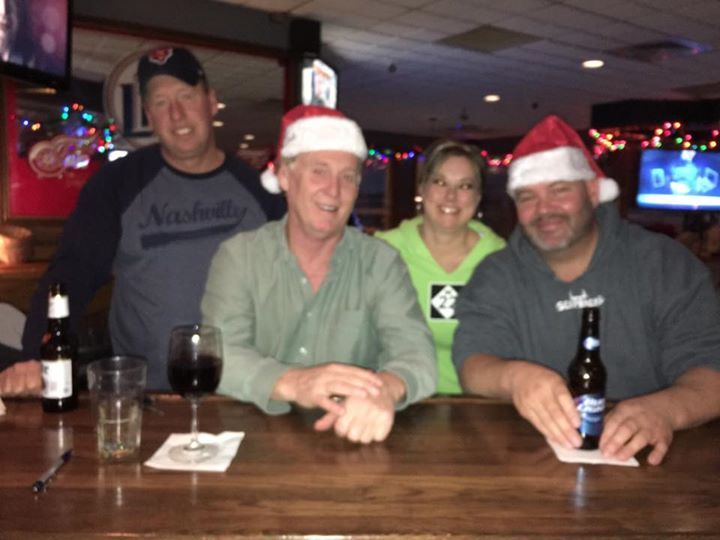 A group of people wearing santa hats are sitting at a bar