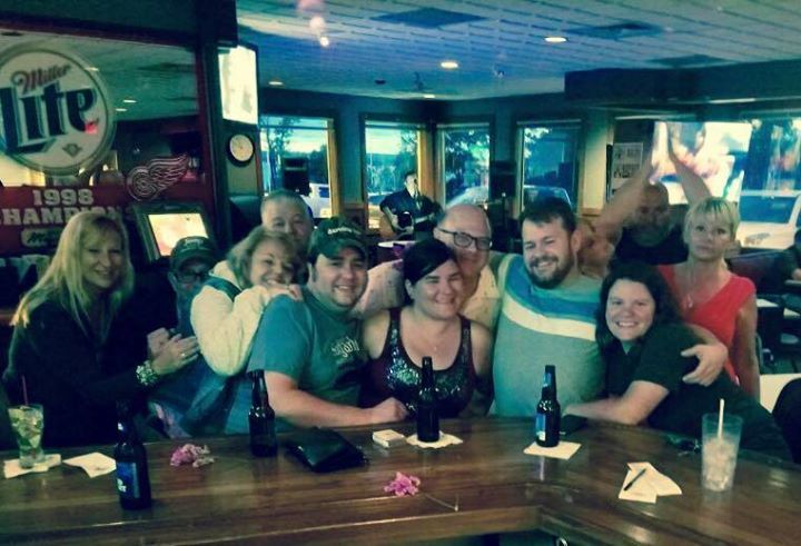 A group of people are posing for a picture at a bar with miller lite in the background