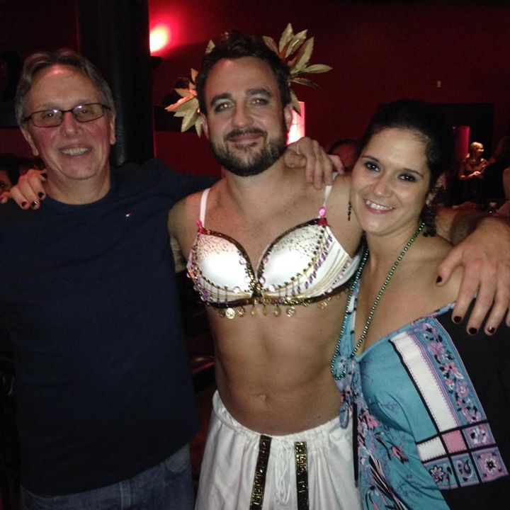 A man in a bra is posing for a picture with two women