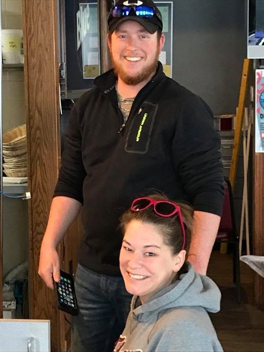 A man and a woman are posing for a picture in a kitchen