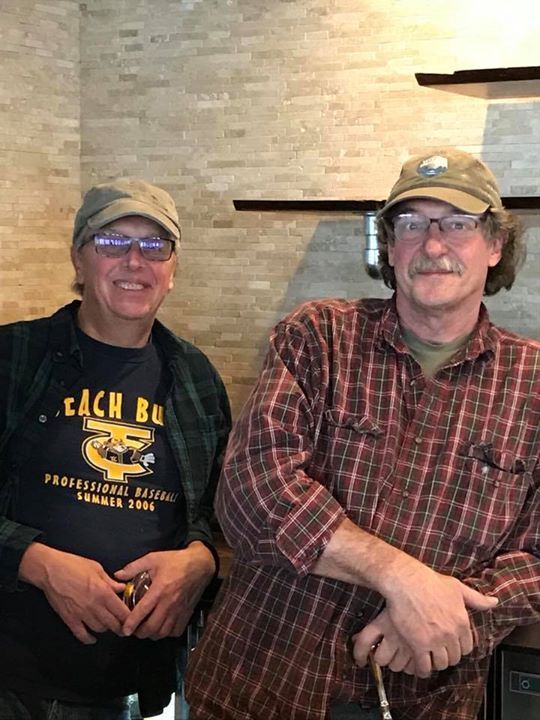 Two men are standing next to each other in a kitchen.