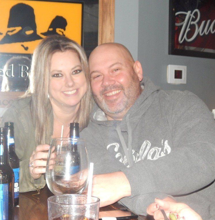 A man and a woman are sitting at a table in front of a budweiser sign
