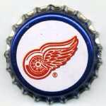 A bottle cap with a red wing on it.