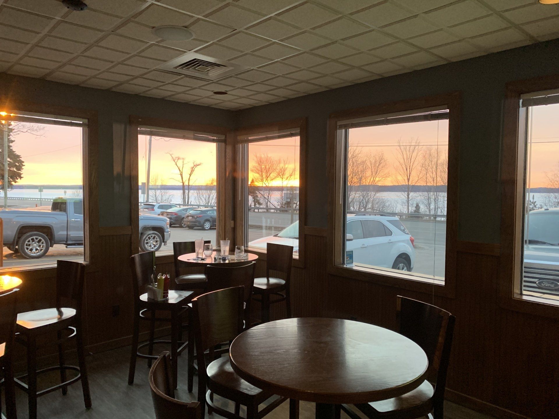 A restaurant with tables and chairs and a sunset in the background.