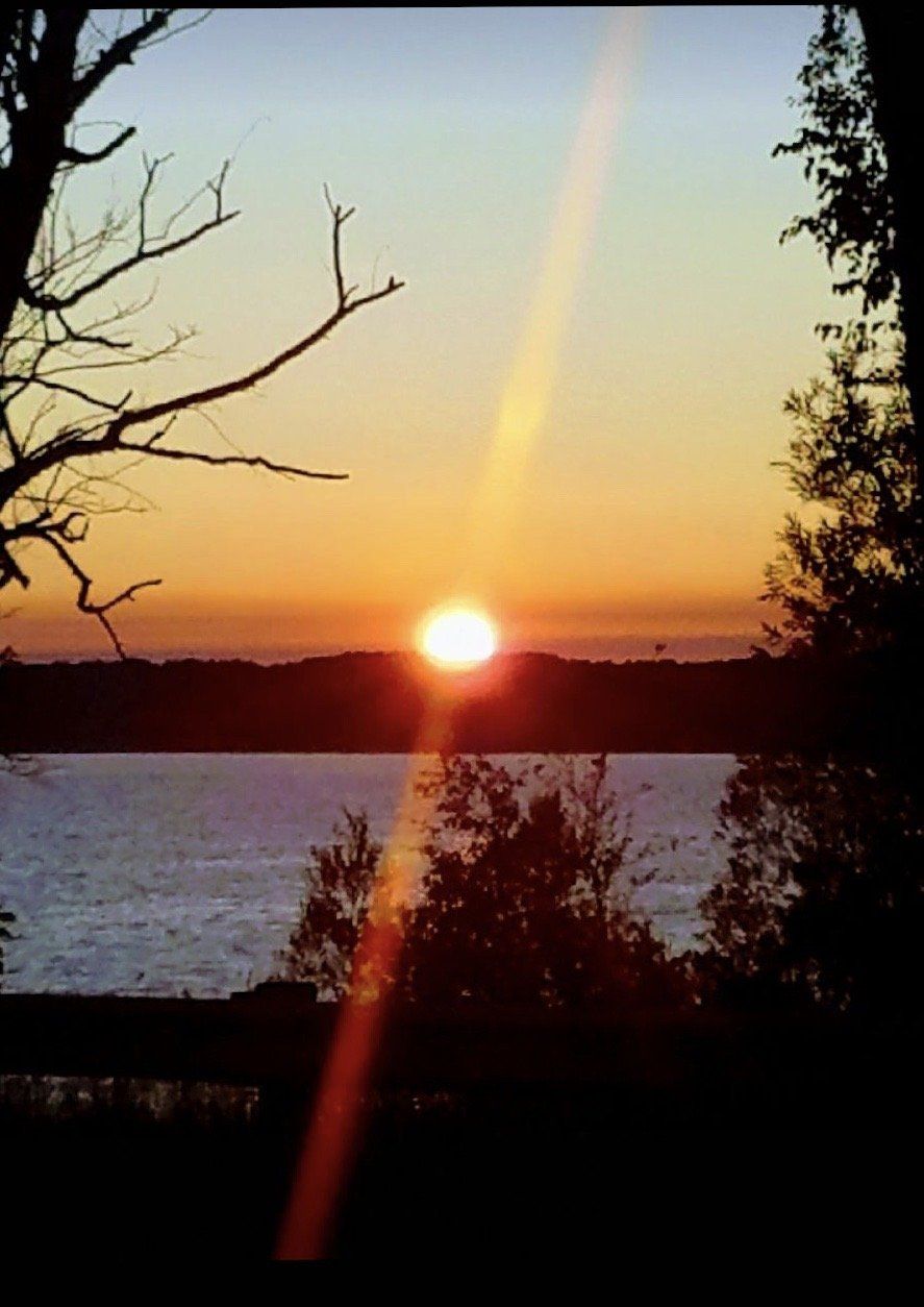 A sunset over a lake with trees in the foreground