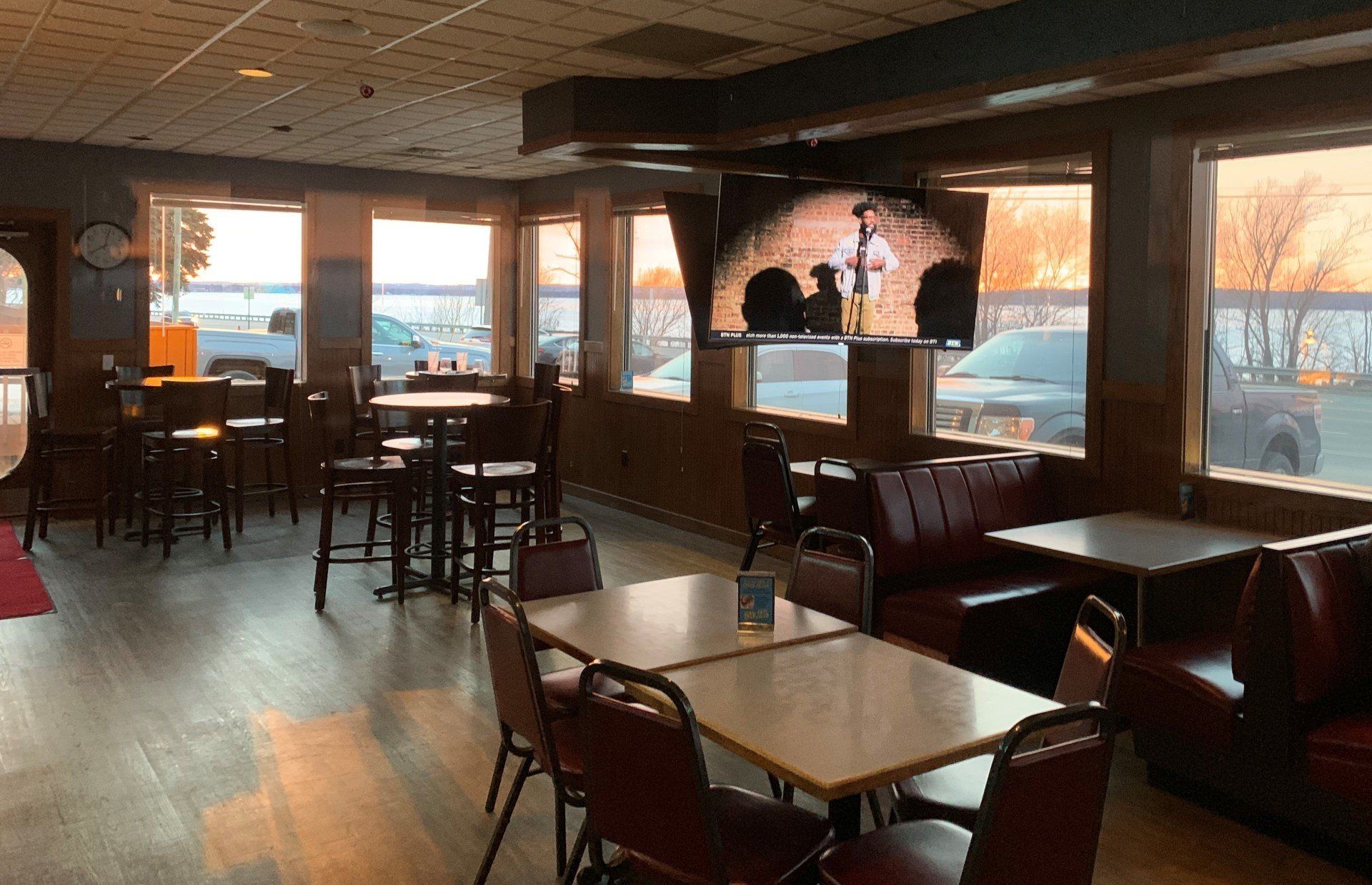A restaurant with tables and chairs and a television on the wall.