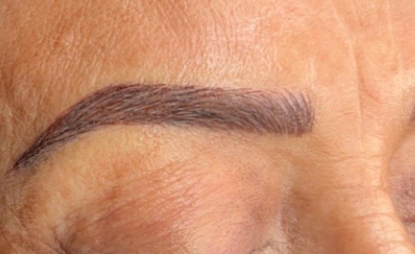 A close up of a woman 's eyebrows with makeup on.