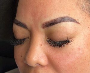 A close up of a woman 's face with her eyes closed and long eyelashes.