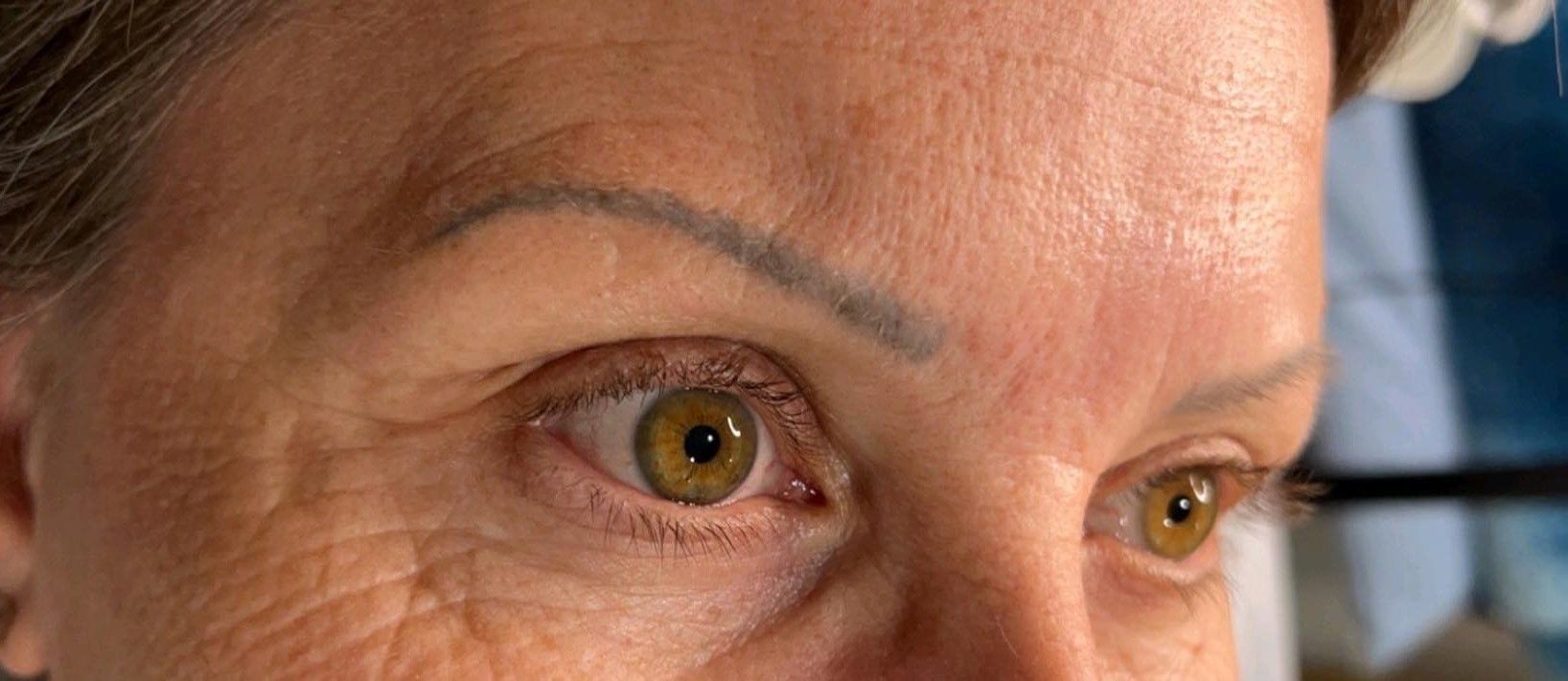 A close up of a woman 's face with a tattoo on her eyebrow.