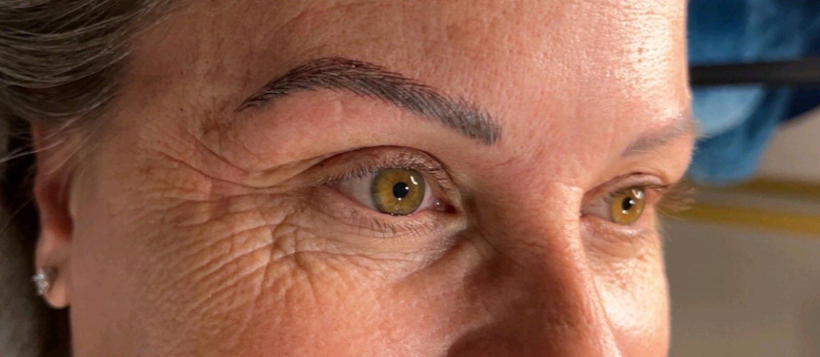 A close up of a woman 's face with a tattoo on her eyebrow.