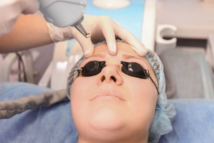 A woman is getting a laser treatment on her face.