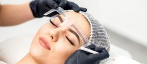 A woman is getting her eyebrows measured in a beauty salon.