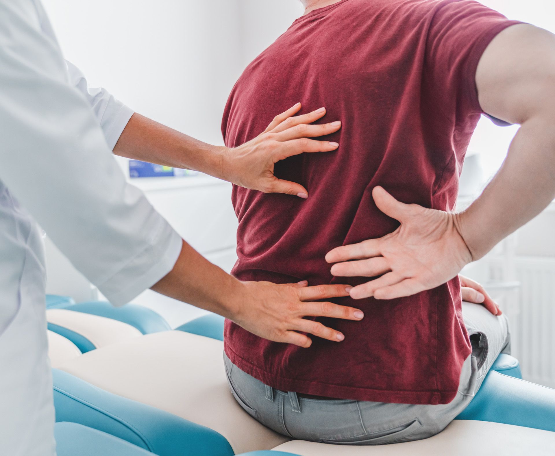 A man is sitting on a table with his hands on his back