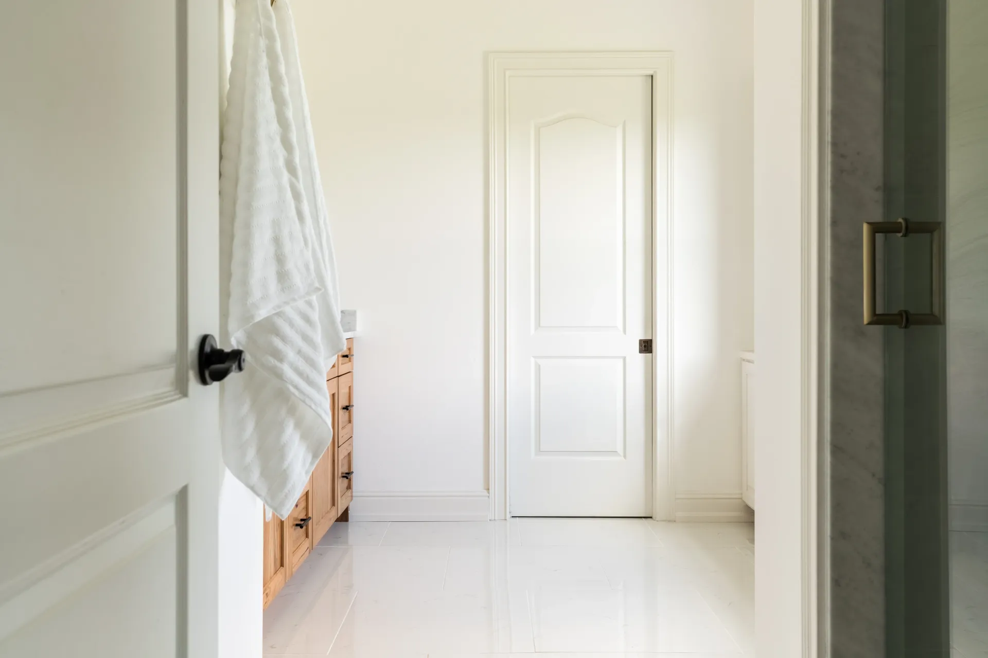 White bathroom interior with door, vanity, and a towel.