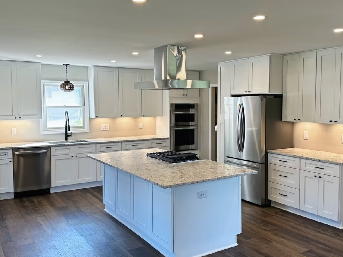 Modern kitchen with white cabinets, stainless steel appliances, and a granite island.