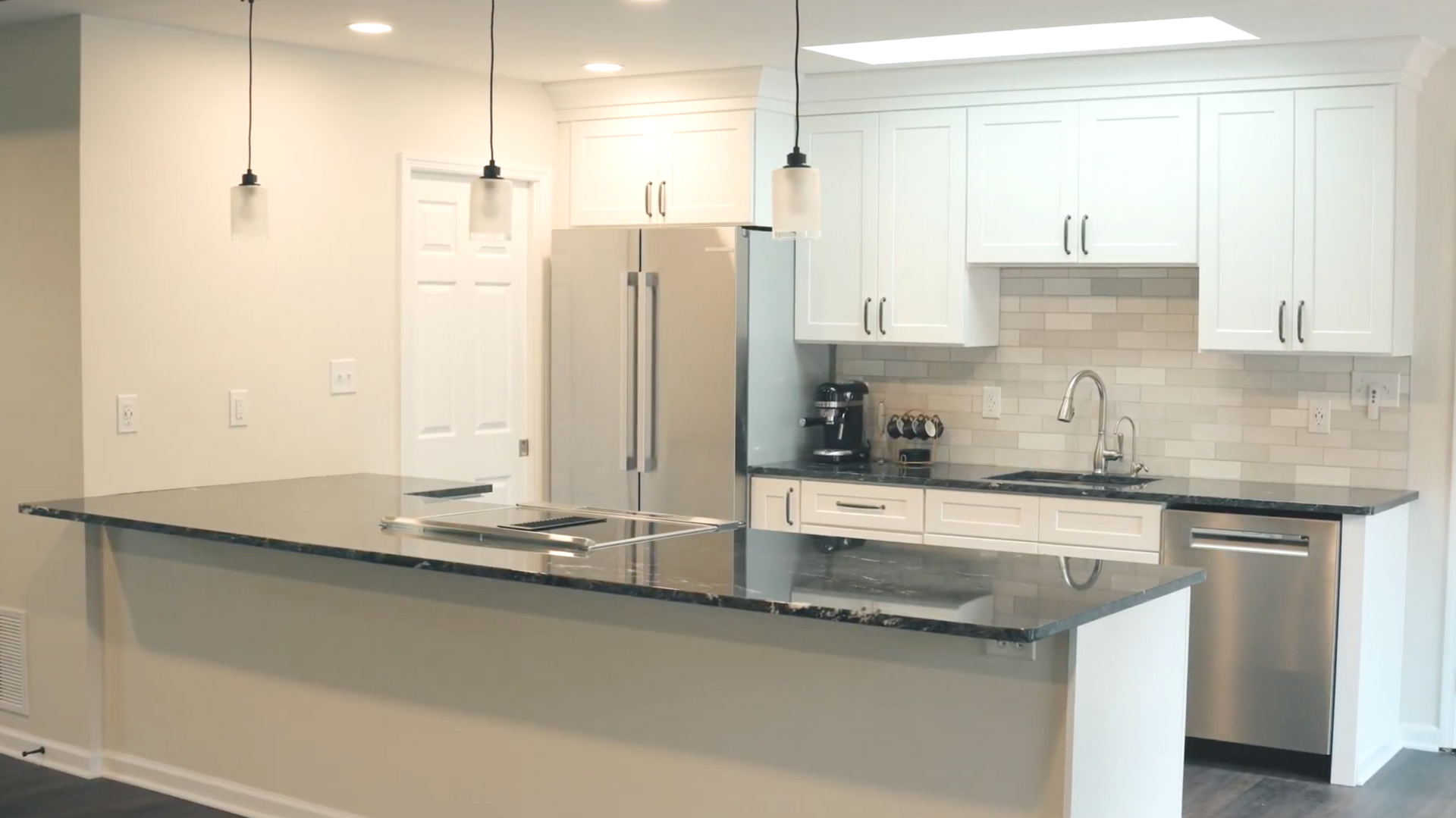 Modern kitchen with white cabinets, stainless steel appliances, and dark granite countertops.