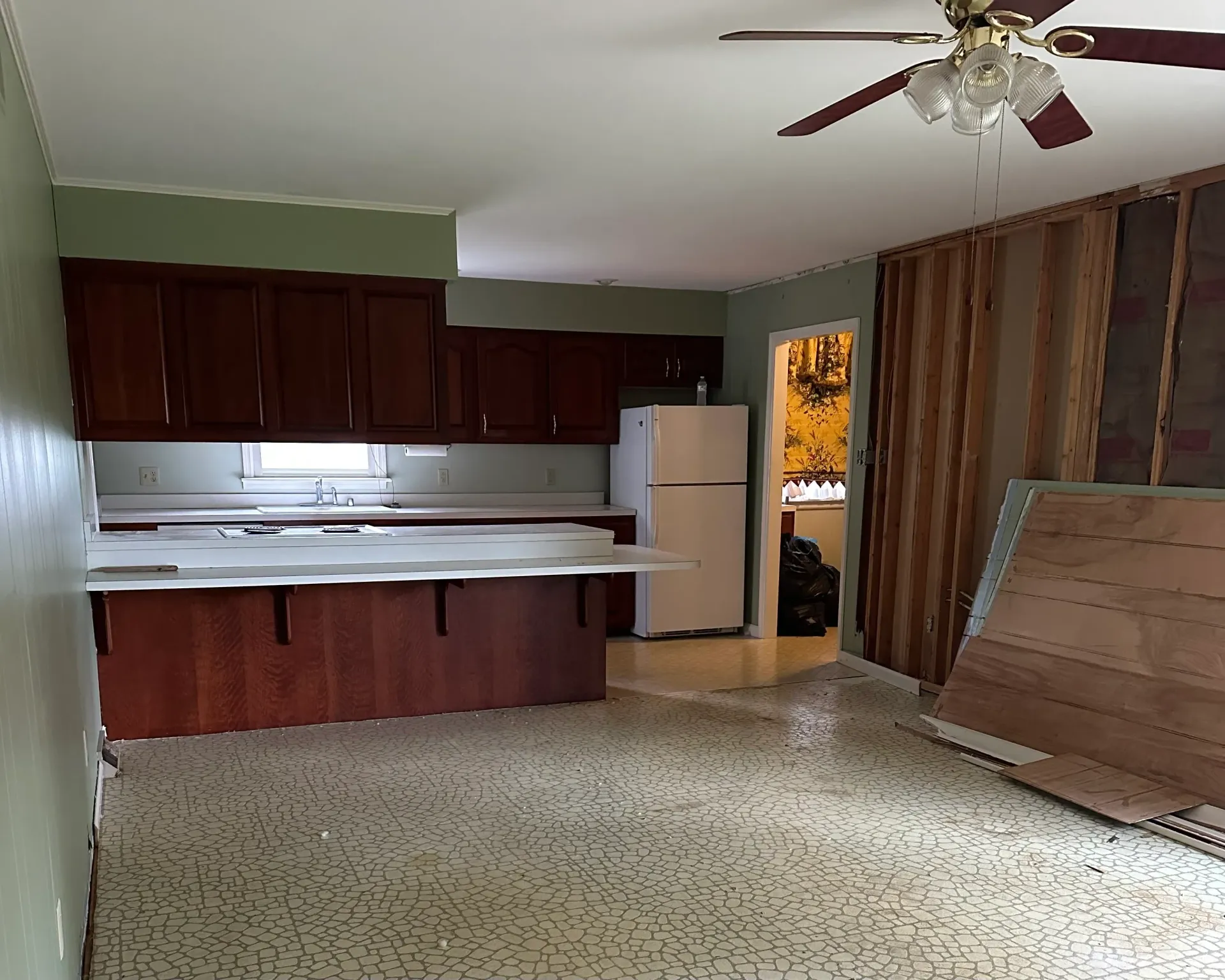 Kitchen interior with dark wood cabinets, white countertops, and exposed wall studs.