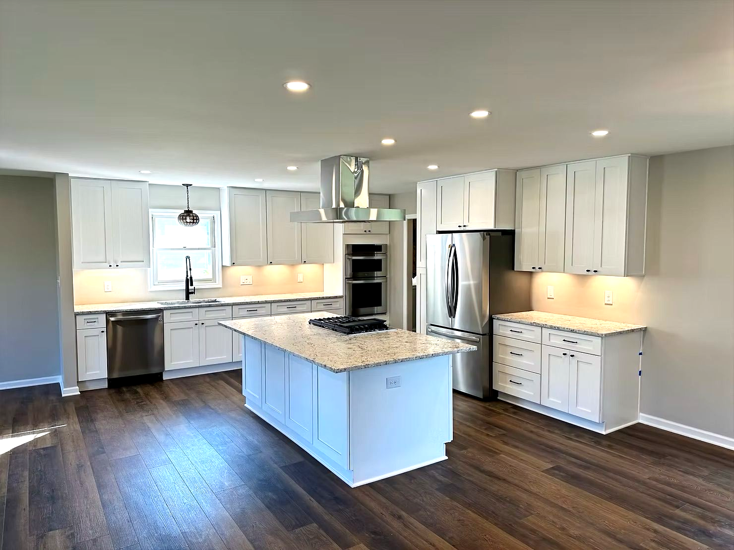 Modern white kitchen with island, stainless steel appliances, and dark wood floors.