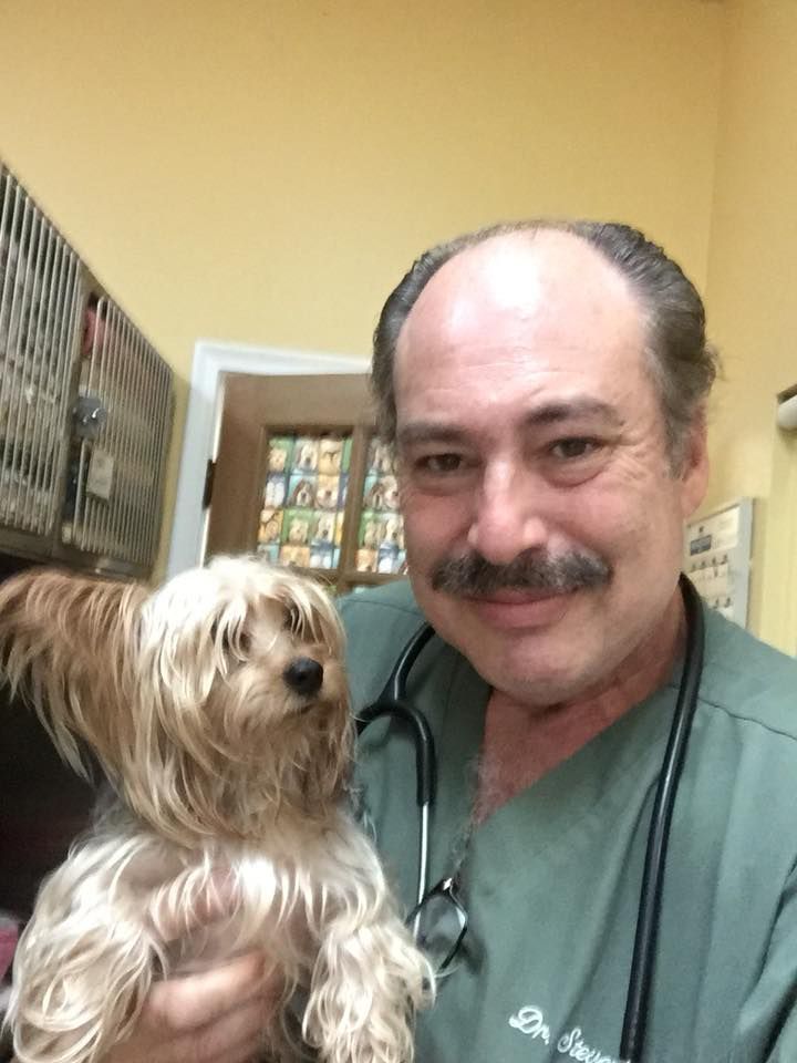 A man with a mustache is holding a small dog.