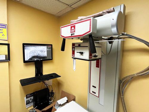 An x-ray machine is sitting in a room next to a computer.