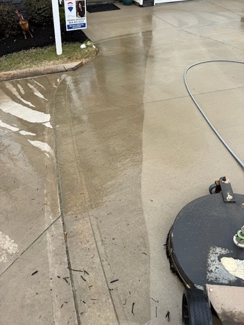 Pressure washing a concrete driveway; cleaner portion visible.