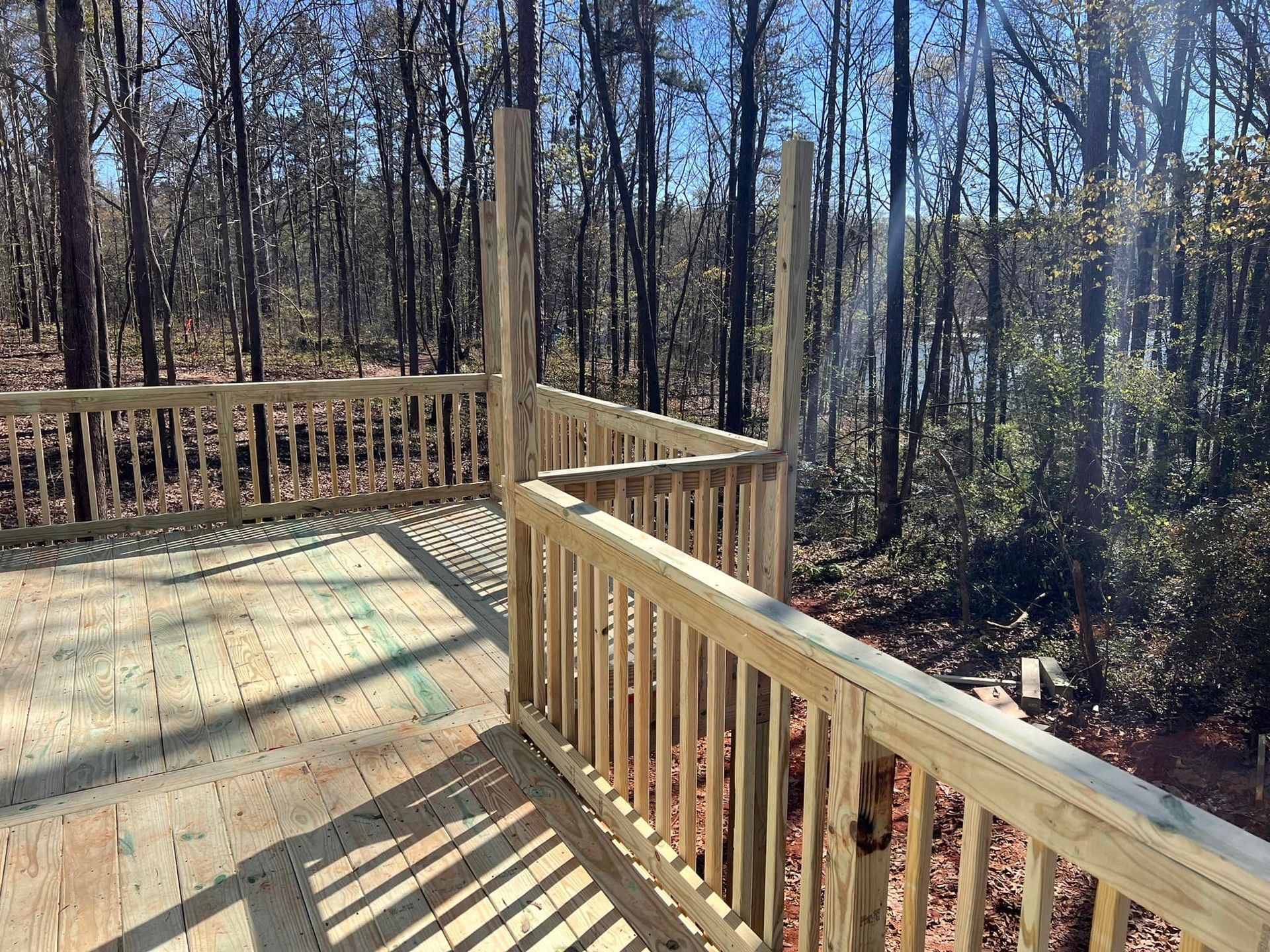Wooden deck with railing in a forest, casting shadows.