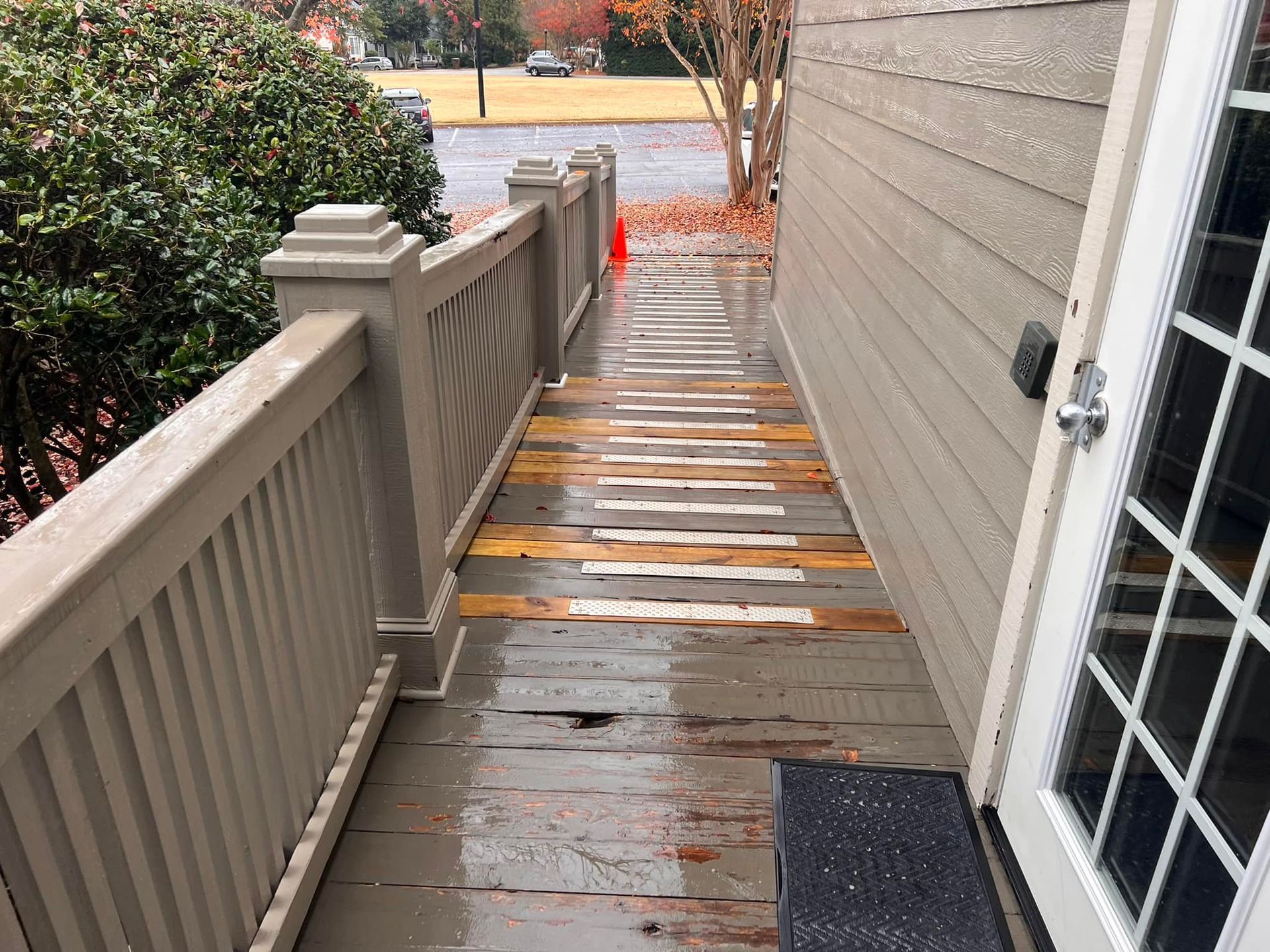 Wooden porch with damaged boards, railings, and a door, exterior shot.