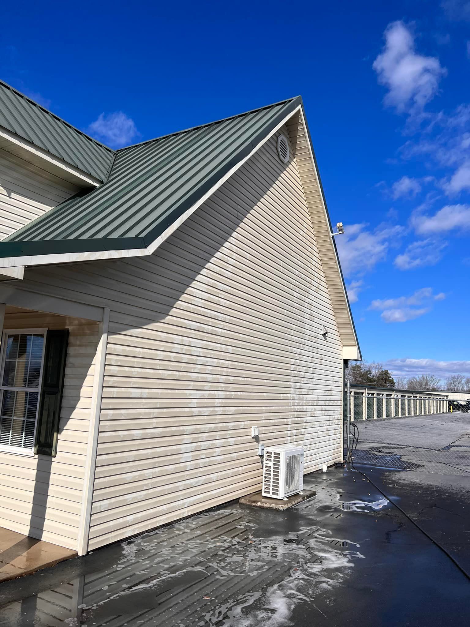 White building with a green roof and a spiraling pattern on the side against a blue sky.