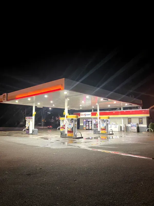 Shell gas station at night; wet pavement reflects bright lights.